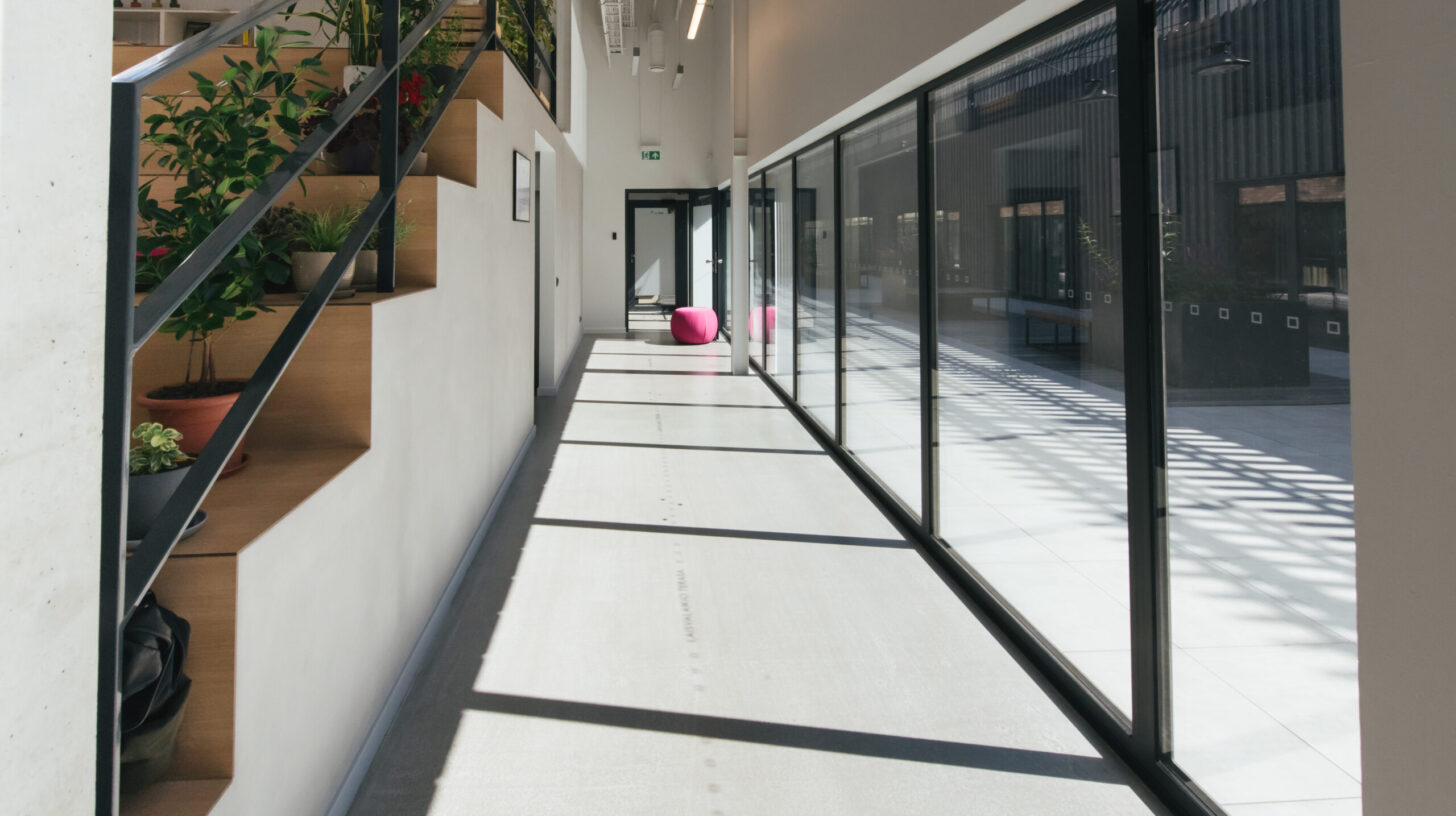 Hallway with windows in light office Perspective view of corridor with glass windows and doorway at end in office interior
